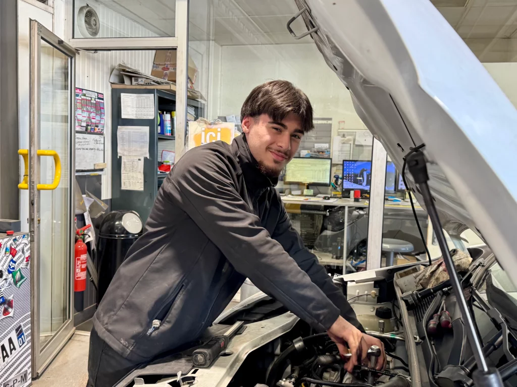Portrait d'un apprenti mécanicien effectuant un changement de bougies dans notre garage Melun Renault Dacia Berard Automobile.